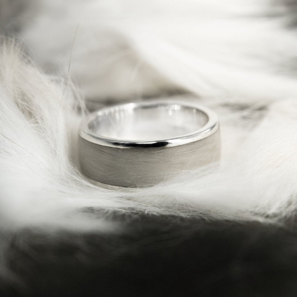 A silver pet hair ring resting on pale fur