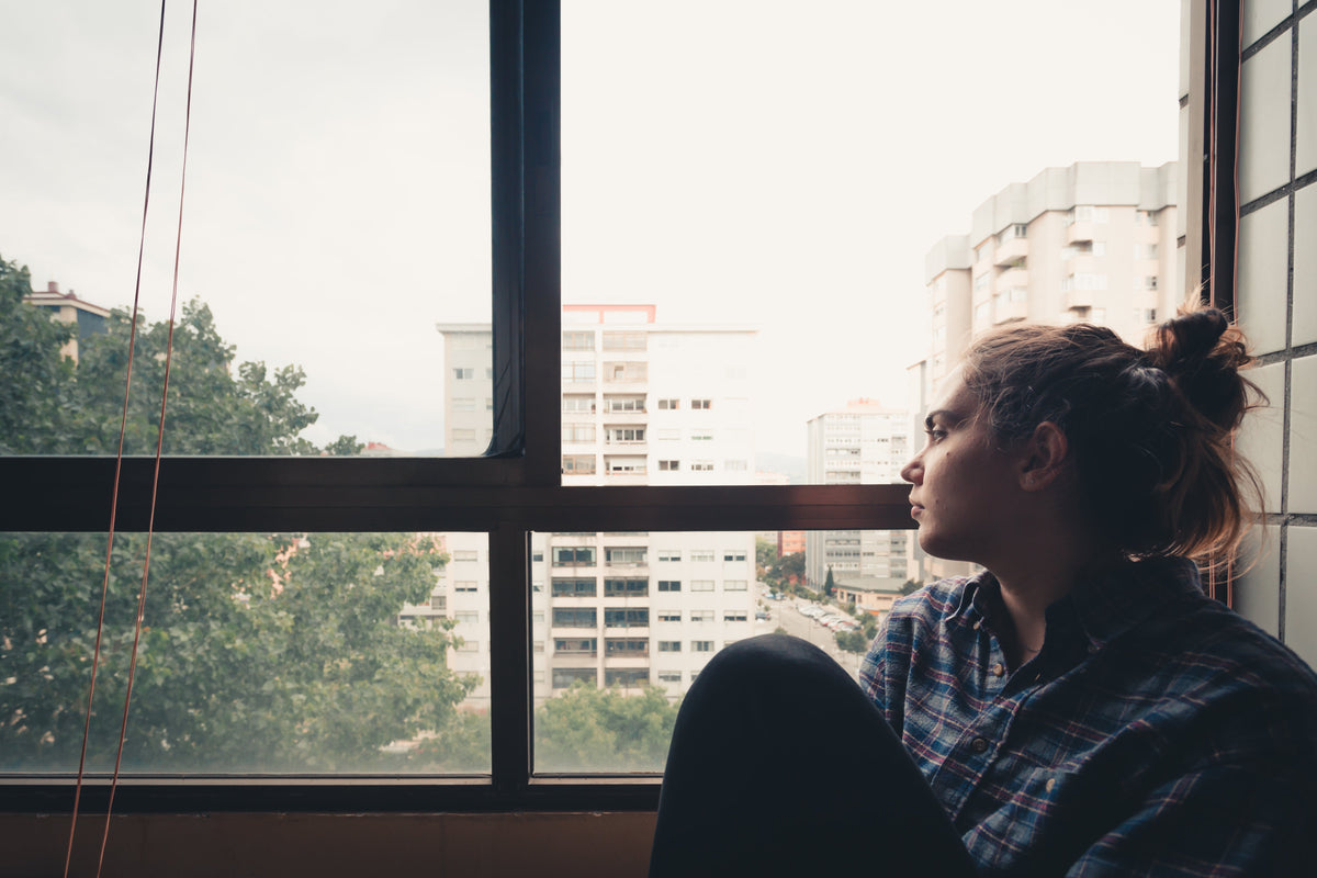 Woman looking through a window in a pet grief support article