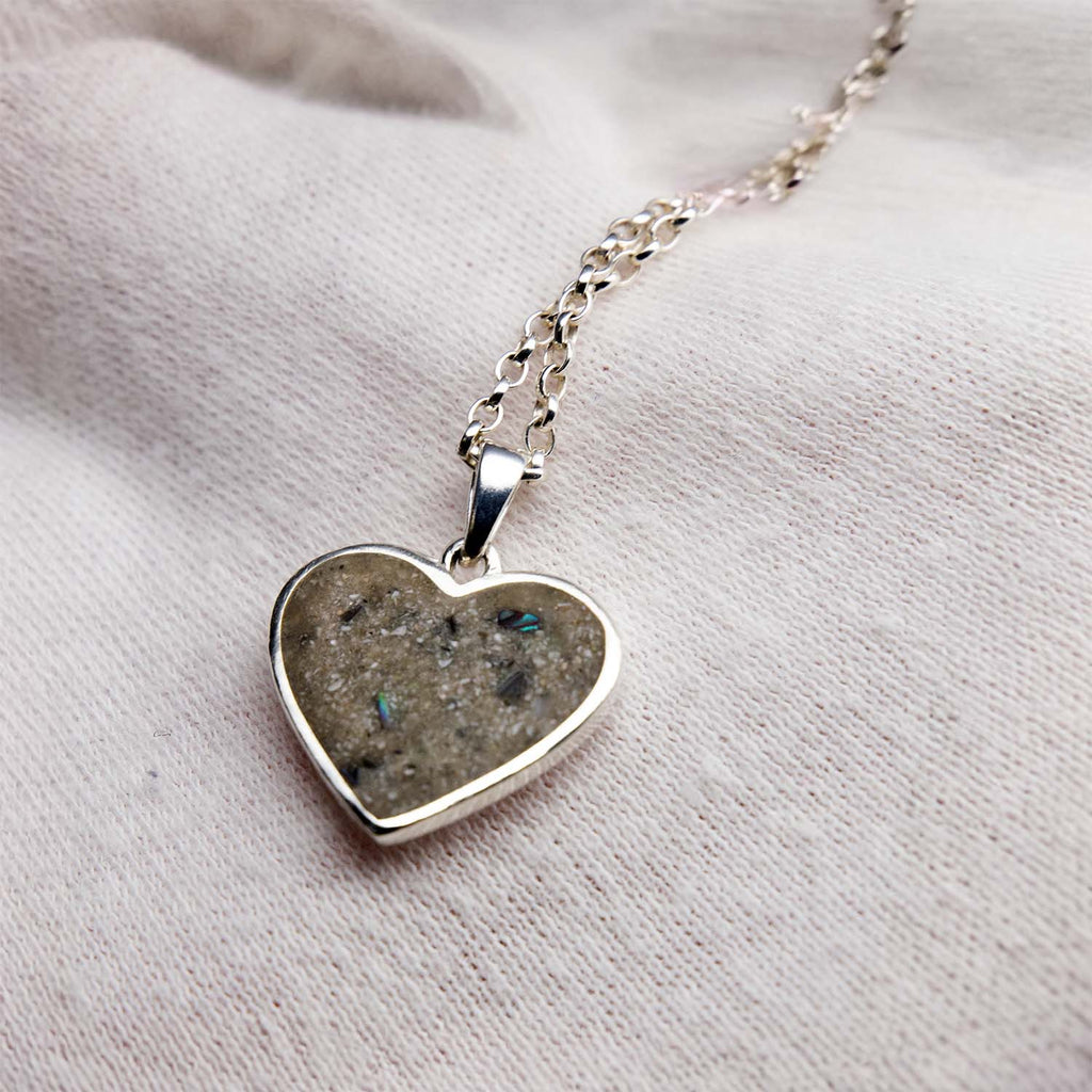 Heart-shaped pendant necklace with a textured surface on a light fabric background
